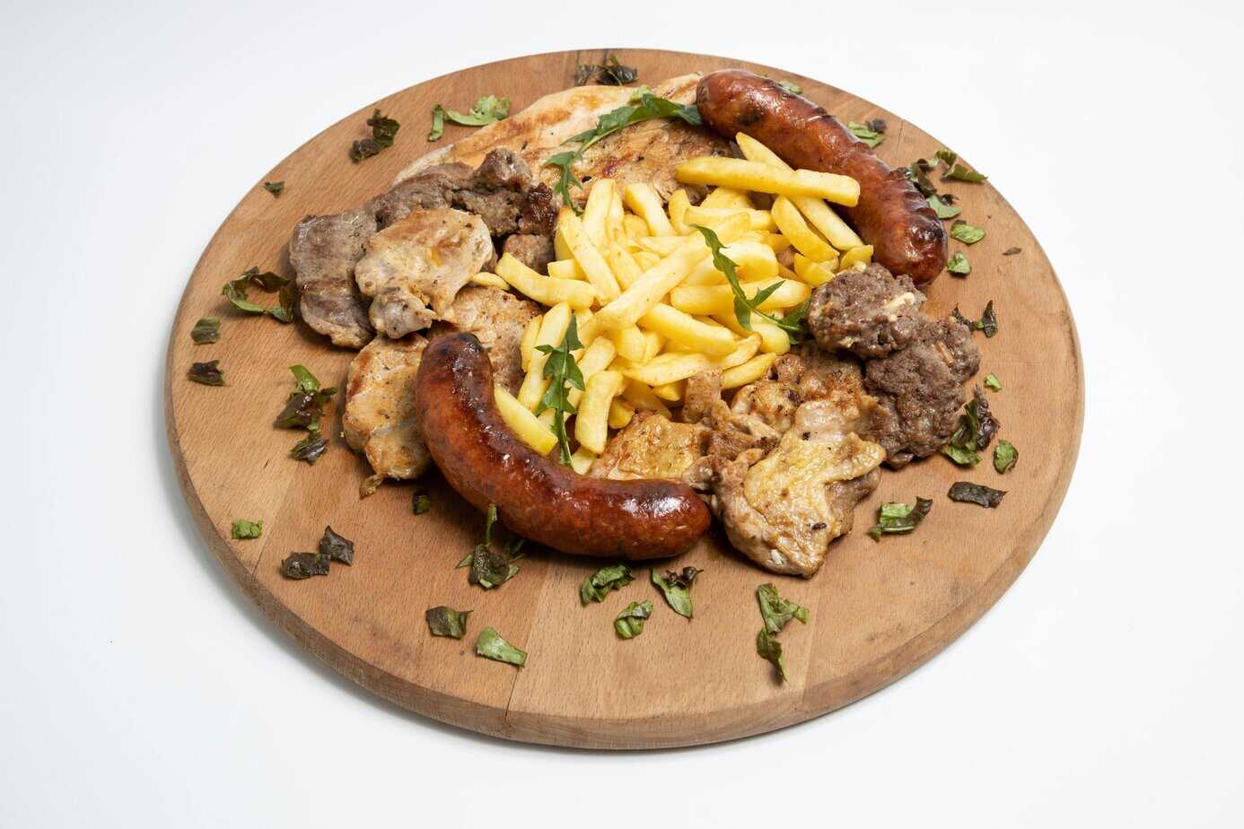 Grilled meal showing how to cook Trader Joe's chicken sausage served with fries, beef, and greens on a wooden plate.