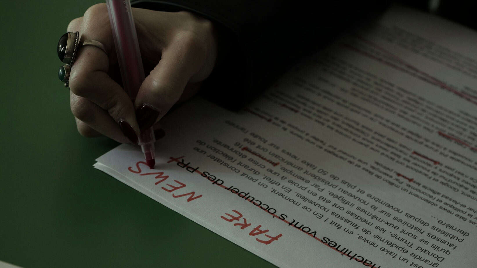 Chicken Sausage Halal or Haram? What You Must Know 1 A close-up of a hand with dark red nail polish using a red pen to write the words "FAKE NEWS" across a printed document