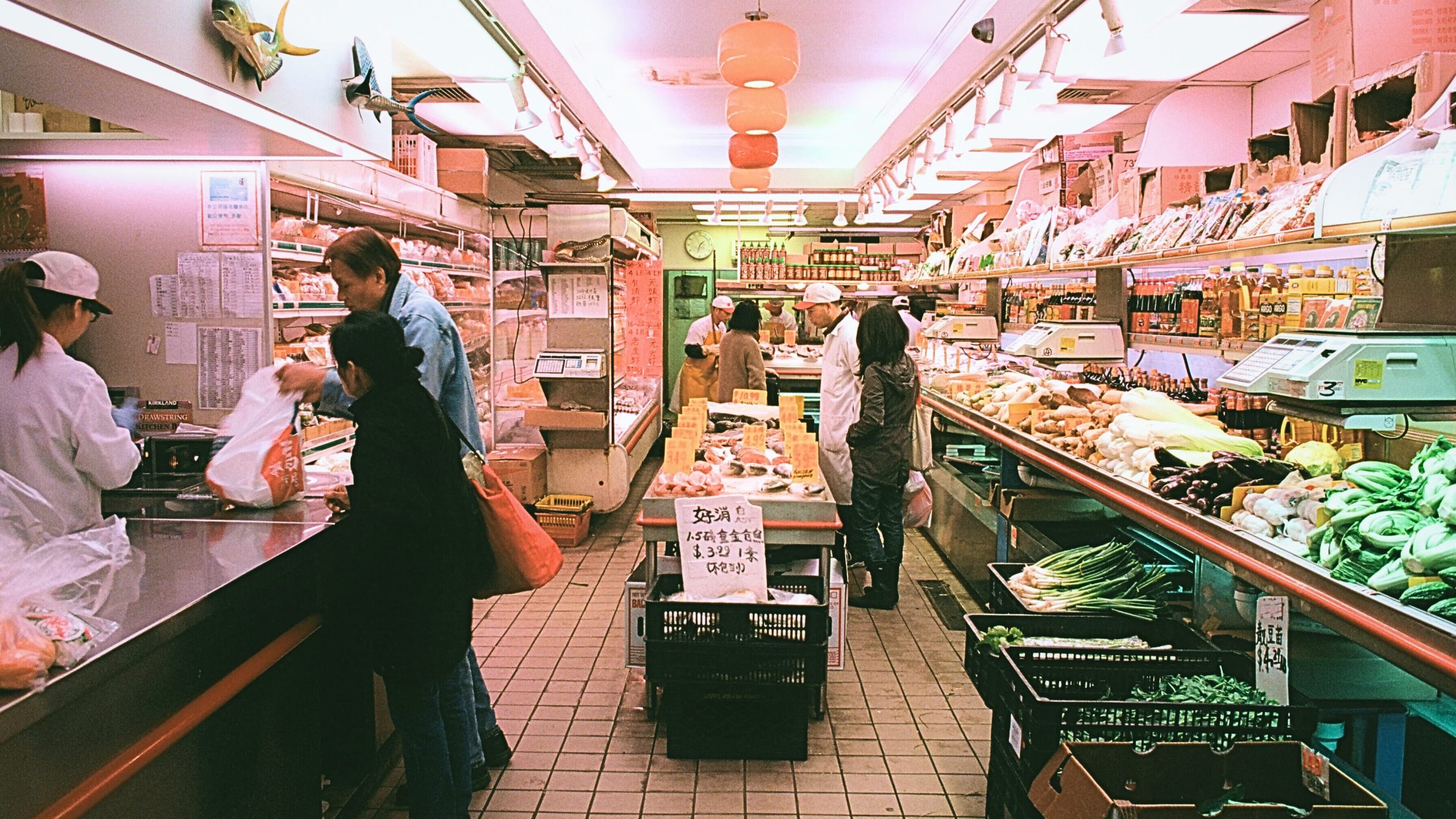 A busy market scene with shoppers selecting fresh produce, showcasing options for buying chicken sausage online.