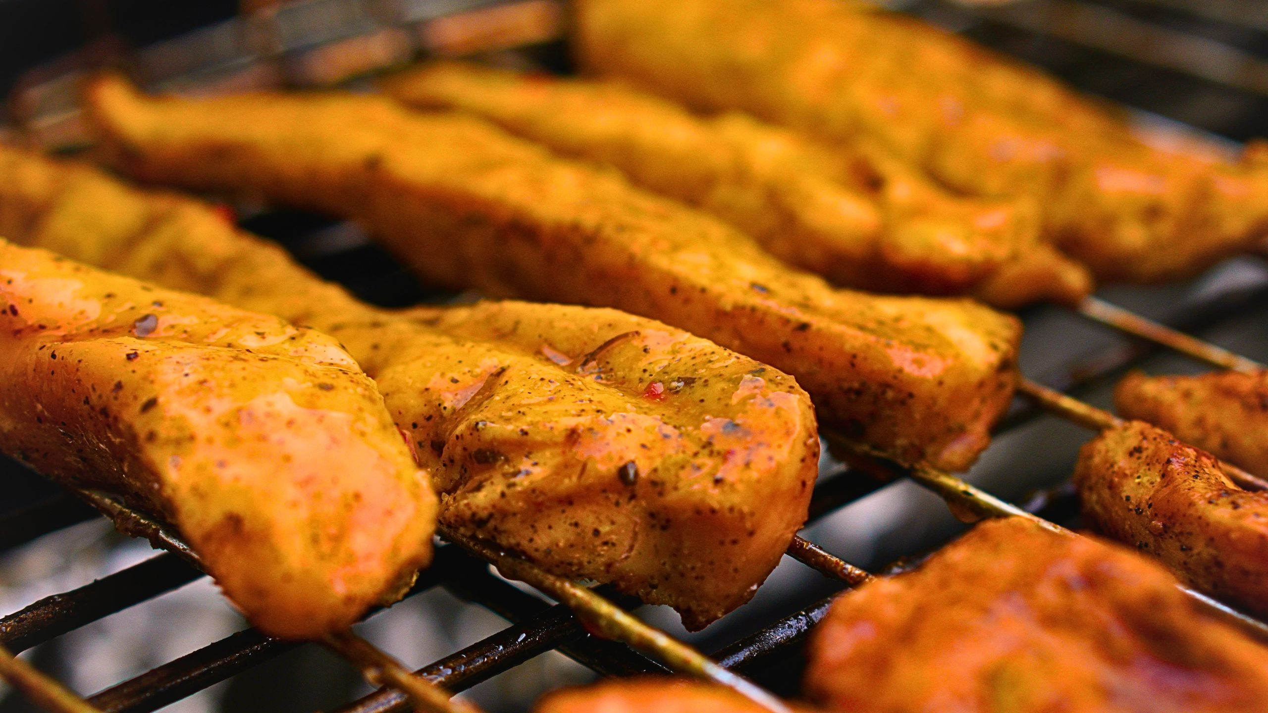 Grilled chicken sausage overcooked, displaying a charred exterior on a barbecue grill, with spices visible.