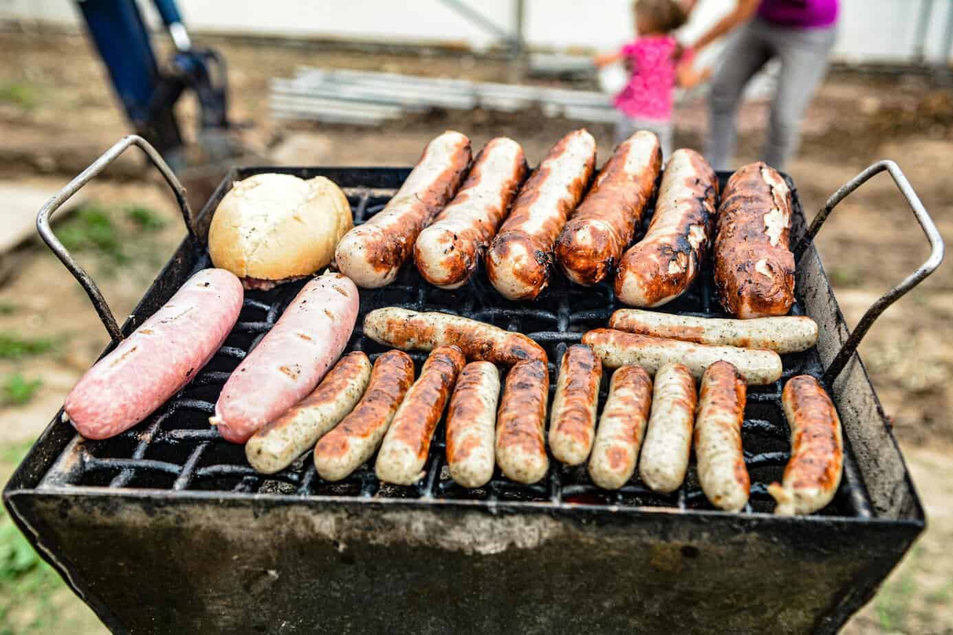 Close-up view of a grill laden with an array of sizzling, seasoned sausages and buns, ready to be enjoyed.