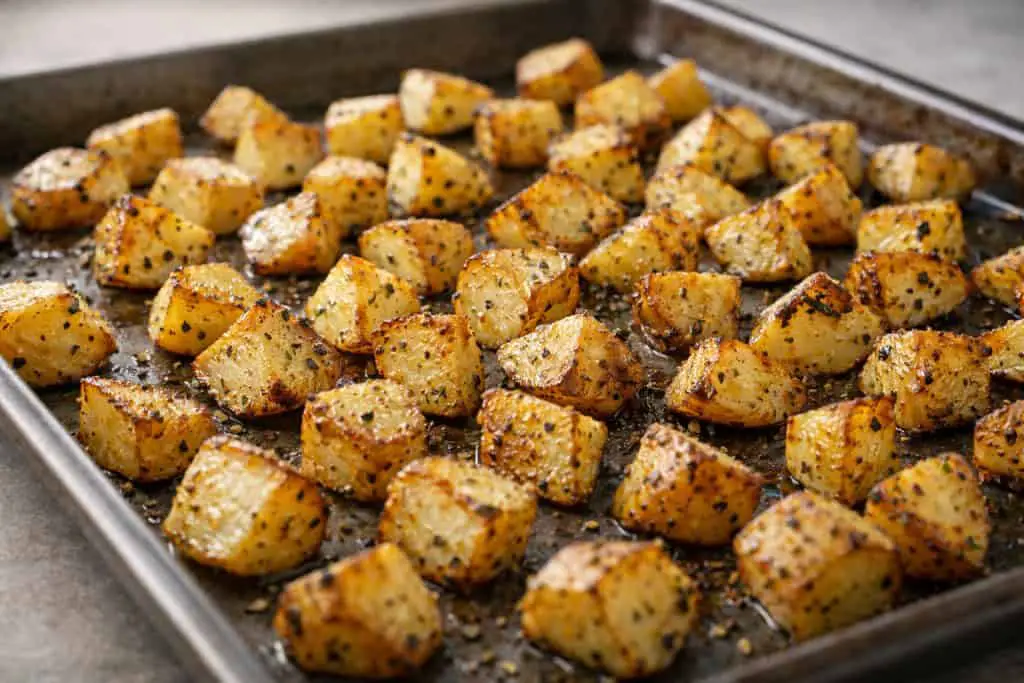 : Crispy roasted potatoes with seasoning, served alongside chicken apple sausage with egg roasted potatoes and an apple on a baking sheet.