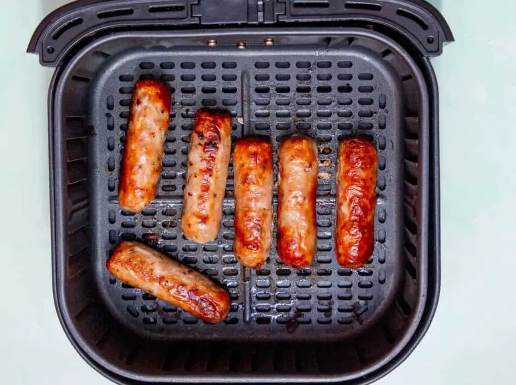 Golden-browned sausages cooked in an air fryer basket, showing perfectly done air fryer chicken sausage results
