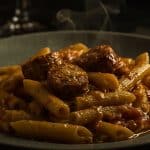 A hearty plate of pasta with tender chicken sausage pieces, coated in a glossy, flavorful sauce that beckons the senses.