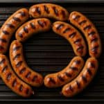 Grilled chicken sausage ring on a cast iron pan, showing how long to grill chicken sausage ring for perfect char marks.