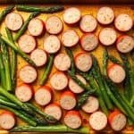 A roasted dish of chicken sausage and asparagus, featuring sliced sausage and vibrant green asparagus on a baking tray.