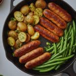 Cooked chicken sausage served in a skillet with roasted potatoes and green beans, styled with Jones sausage packaging for a healthy meal presentation.
