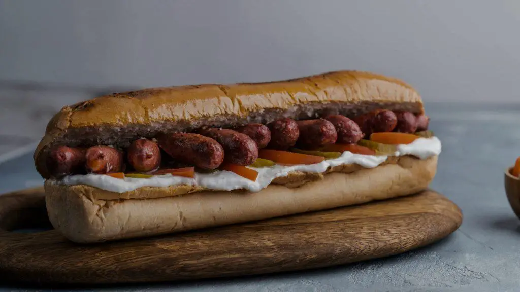 A large submarine sandwich filled with small chicken sausages, illustrating the best way to prepare them.