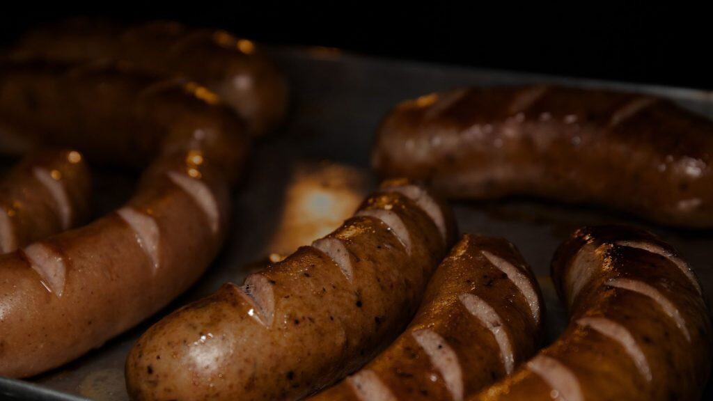 Cooked chicken sausages with grill marks on a tray, relevant to "does chicken sausage have iron.”