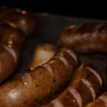 Cooked chicken sausages with grill marks on a tray, relevant to "does chicken sausage have iron.”