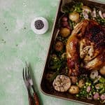 Top view of Chicken and Sausage Tray Bake Nigella style with roasted potatoes, peas, garlic, and herbs in a baking tray.