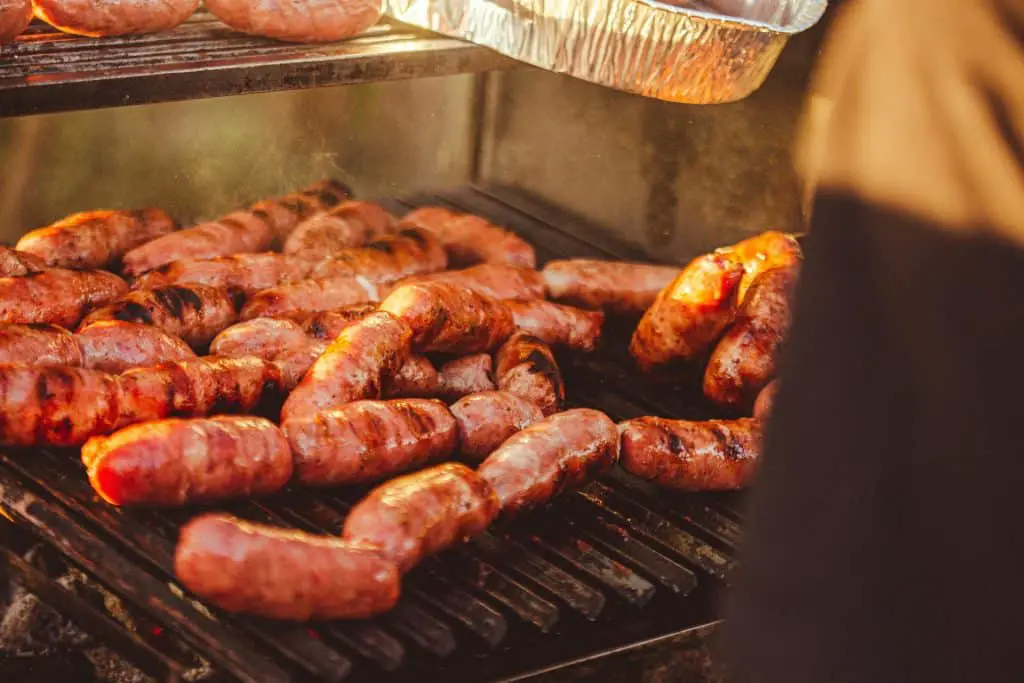 Sizzling sausages cooking on a hot grill, releasing a mouthwatering aroma.