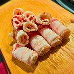 Sliced chicken sausage overcooked, arranged neatly on a wooden board, showcasing its texture and color.