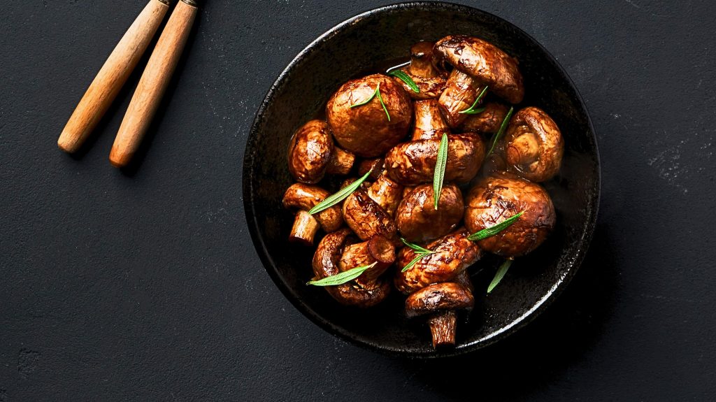 A bowl of sautéed mushrooms garnished with herbs, perfect for a Chicken Sausage Veggie Bake. Credit: unsplash.com (photo by Alex Bayev)