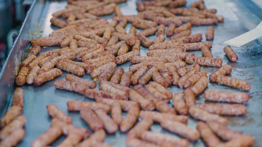 A large spread of Chicken Sausage with Pork Casing on a metal tray, showcasing their brown, crispy texture.