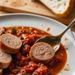 Savory chicken sausage slices bathed in a vibrant marinara sauce, creating a hearty and flavorful dish served with freshly baked bread.