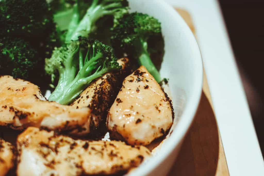 Cooked chicken sausage and broccoli in a white bowl, showcasing a healthy dish for a chicken sausage sheet pan meal.