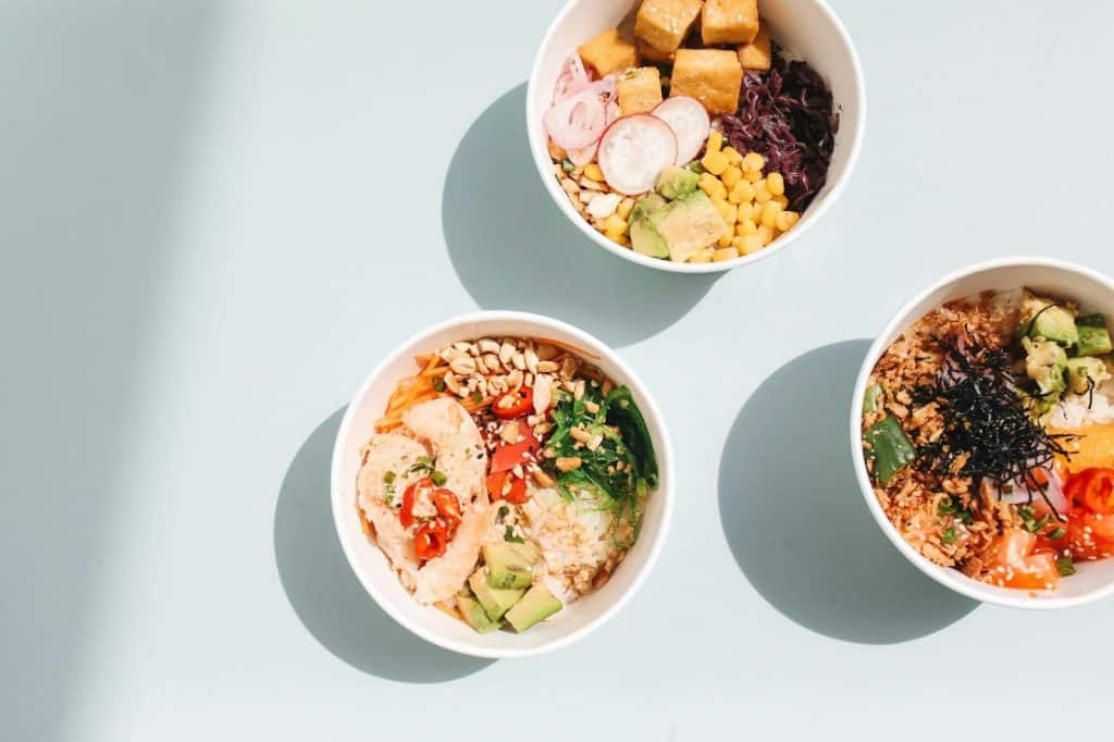 Colorful bowls of healthy vegetarian dishes, featuring various grains, vegetables, and toppings.