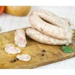 Raw chicken sausage links sliced on a wooden board with herbs and peppercorns — Is Chicken Sausage Low-Fat compared to pork?