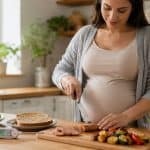 Pregnant woman slicing chicken sausage pregnancy safe meal with food thermometer nearby